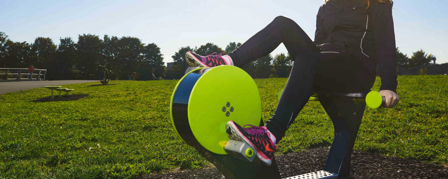 Young lady on outdoor static bike in a park
