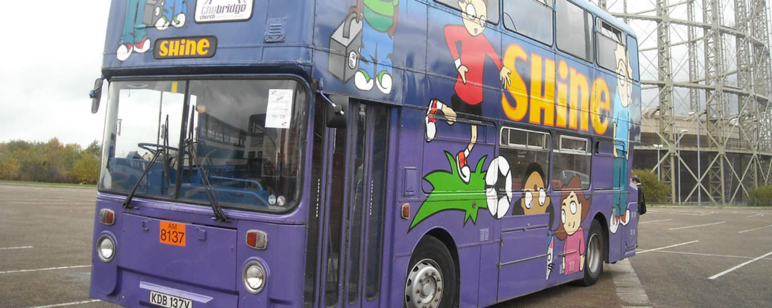 Double Decker bus bright purple with colourful cartoon pictures of children